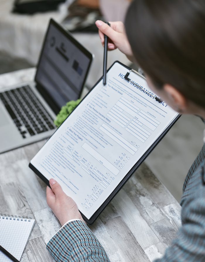 why-choose-us An adult reviews a home insurance policy document at a desk with a pen and laptop.
