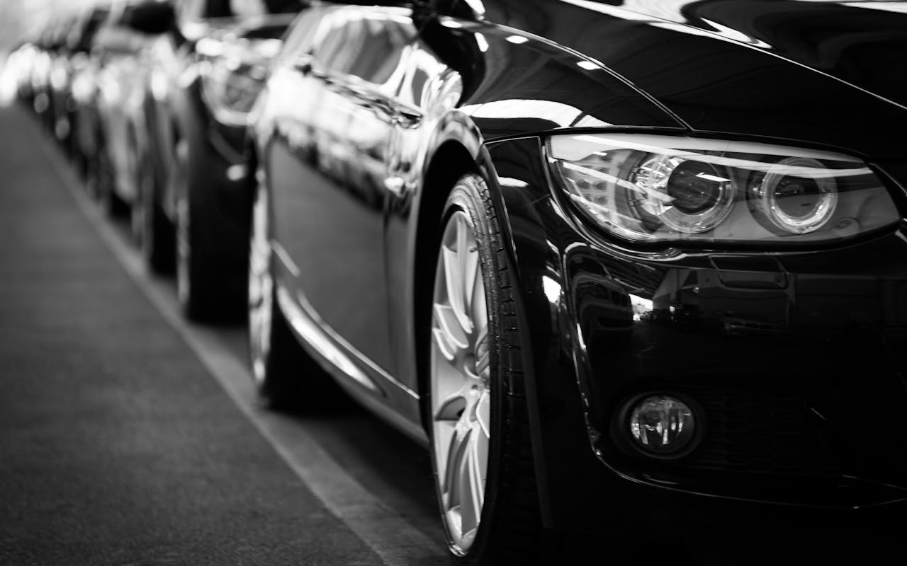 Services-01 Close-up black and white image of a luxury car line-up focusing on vehicle headlights.