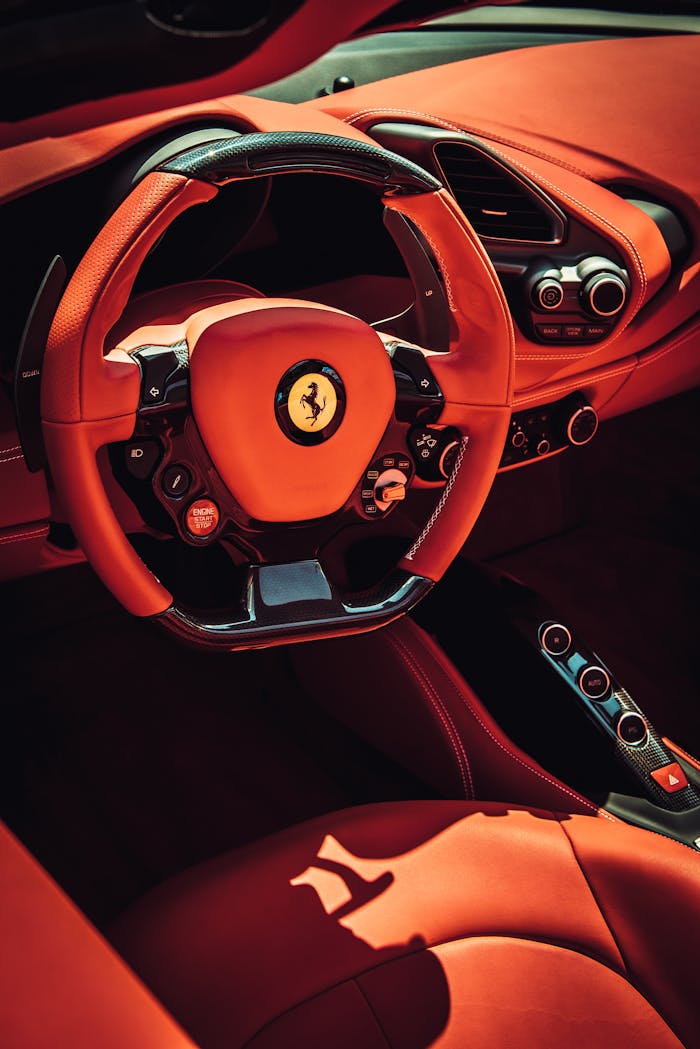 creative-01 Close-up of a luxurious red interior of a sports car featuring a stylish steering wheel.