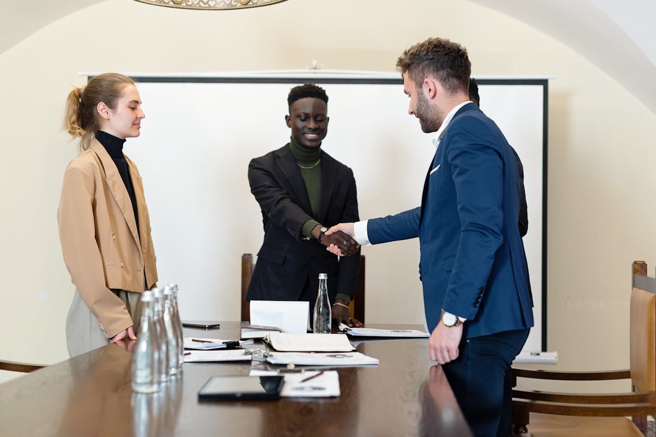 digital A diverse group of business professionals in a meeting room, shaking hands as a sign of agreement.