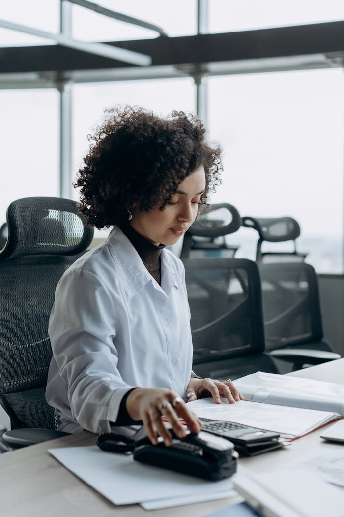 creative Young woman with curly hair working at a modern office desk, calculating numbers with focus.